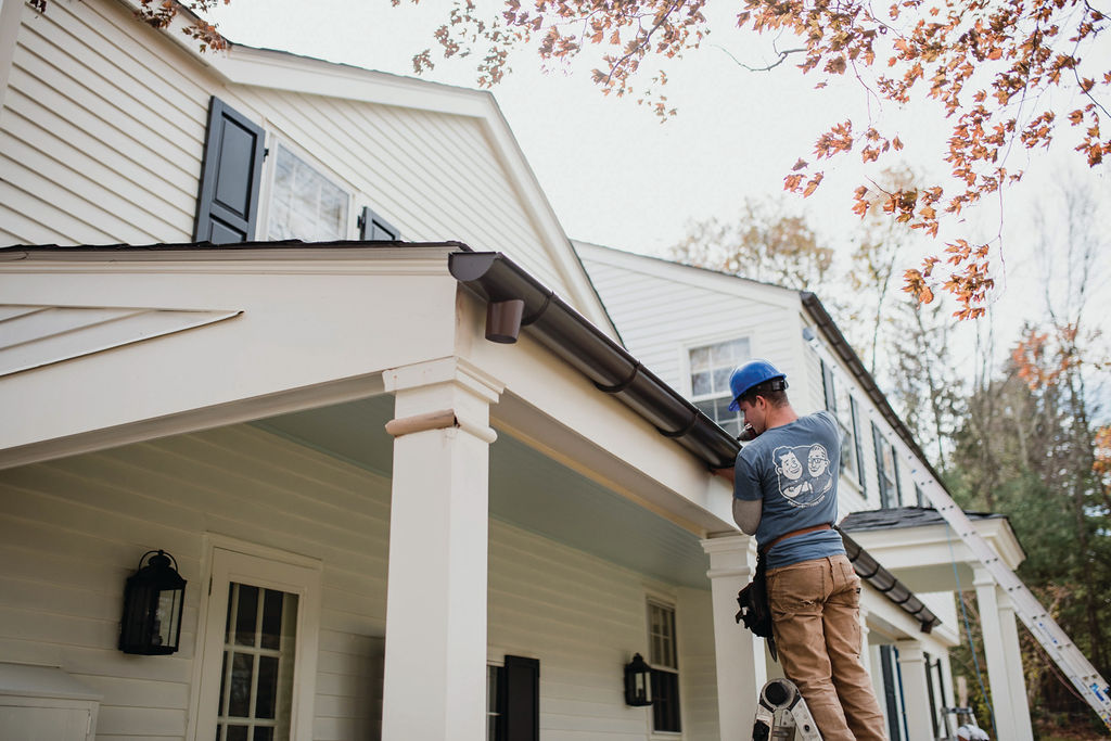 gutter installation tech on ladder installing a gutter on a home