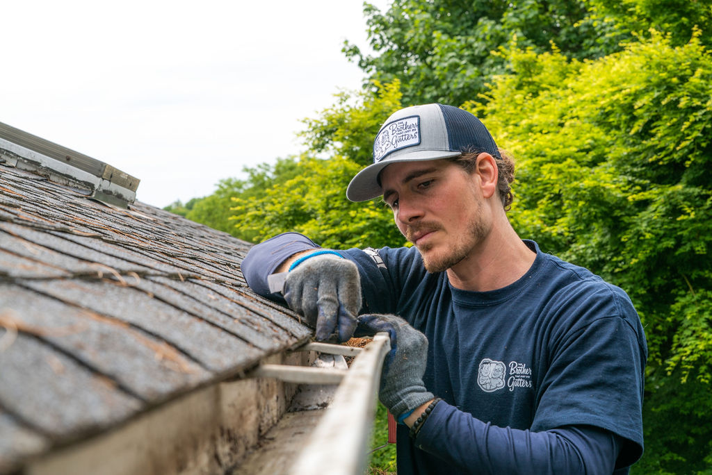 gutter contractors - technician cleaning a gutter