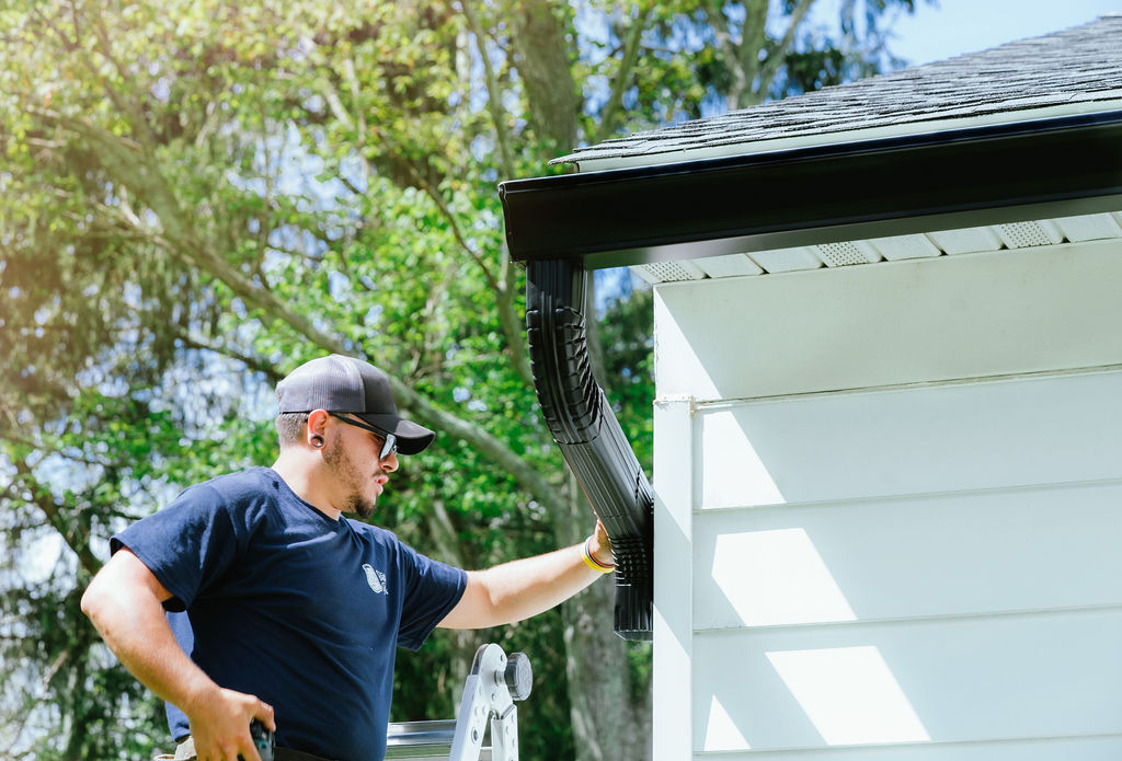 gutter installation services - technician installing gutters and downspouts