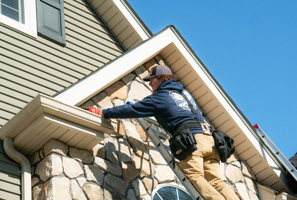 gutter services - tech performing a gutter installation on a ladder