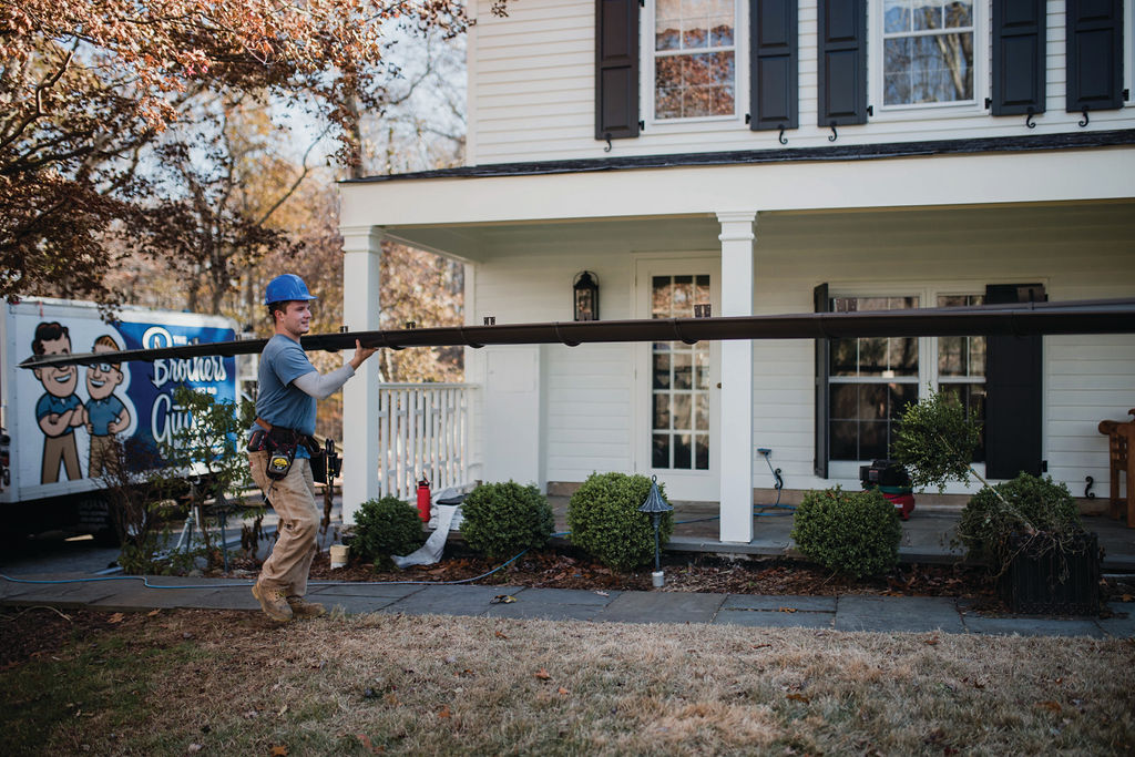 gutter installation tech carrying a gutter to the house