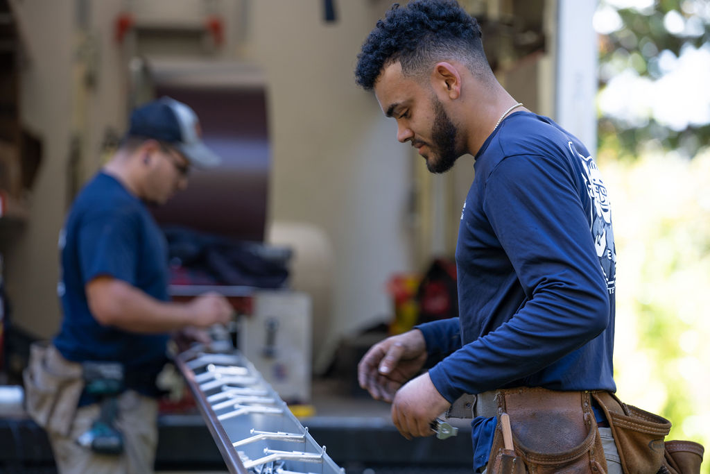 gutter contractor services - installers prepping a gutter to be installed on a home