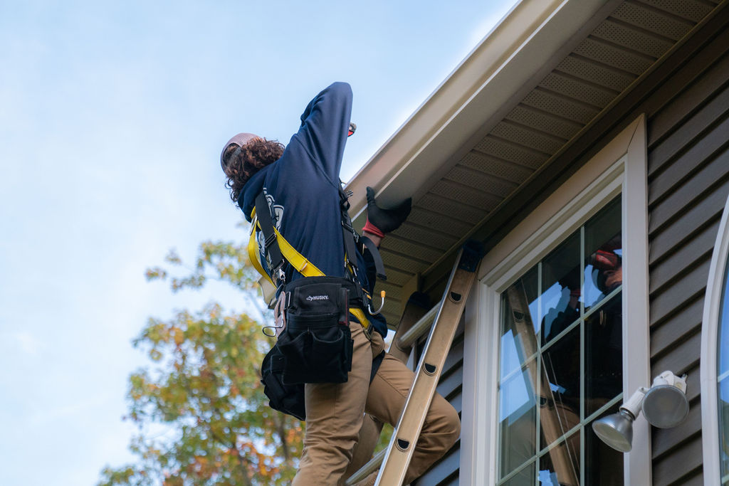 gutter contractor on ladder repairing a gutter