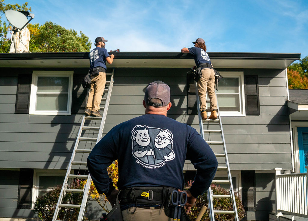 gutter contractors working on a gutter from ladders