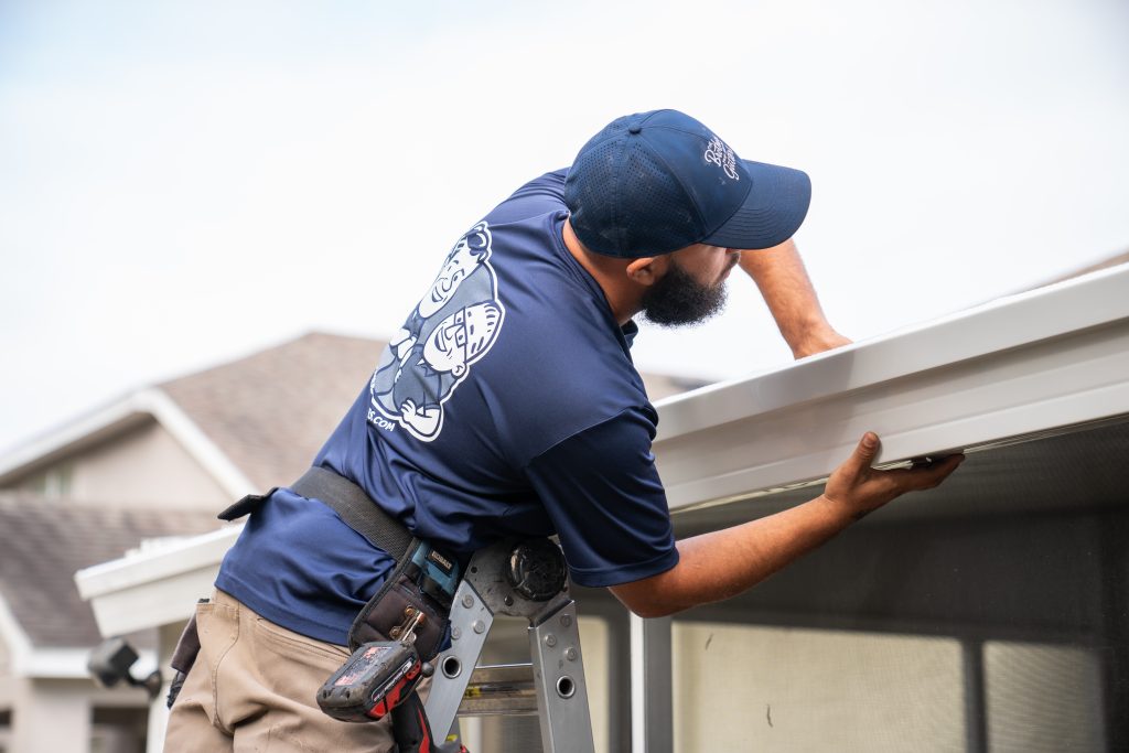 Brothers Gutters installer works to install a brown gutter